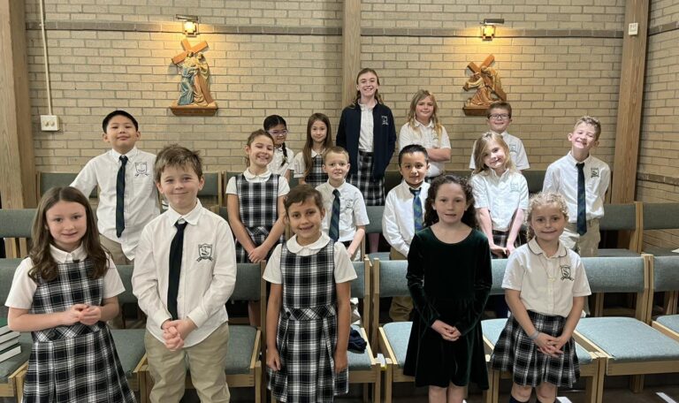 Students in Catholic school uniforms stand in choir area of church