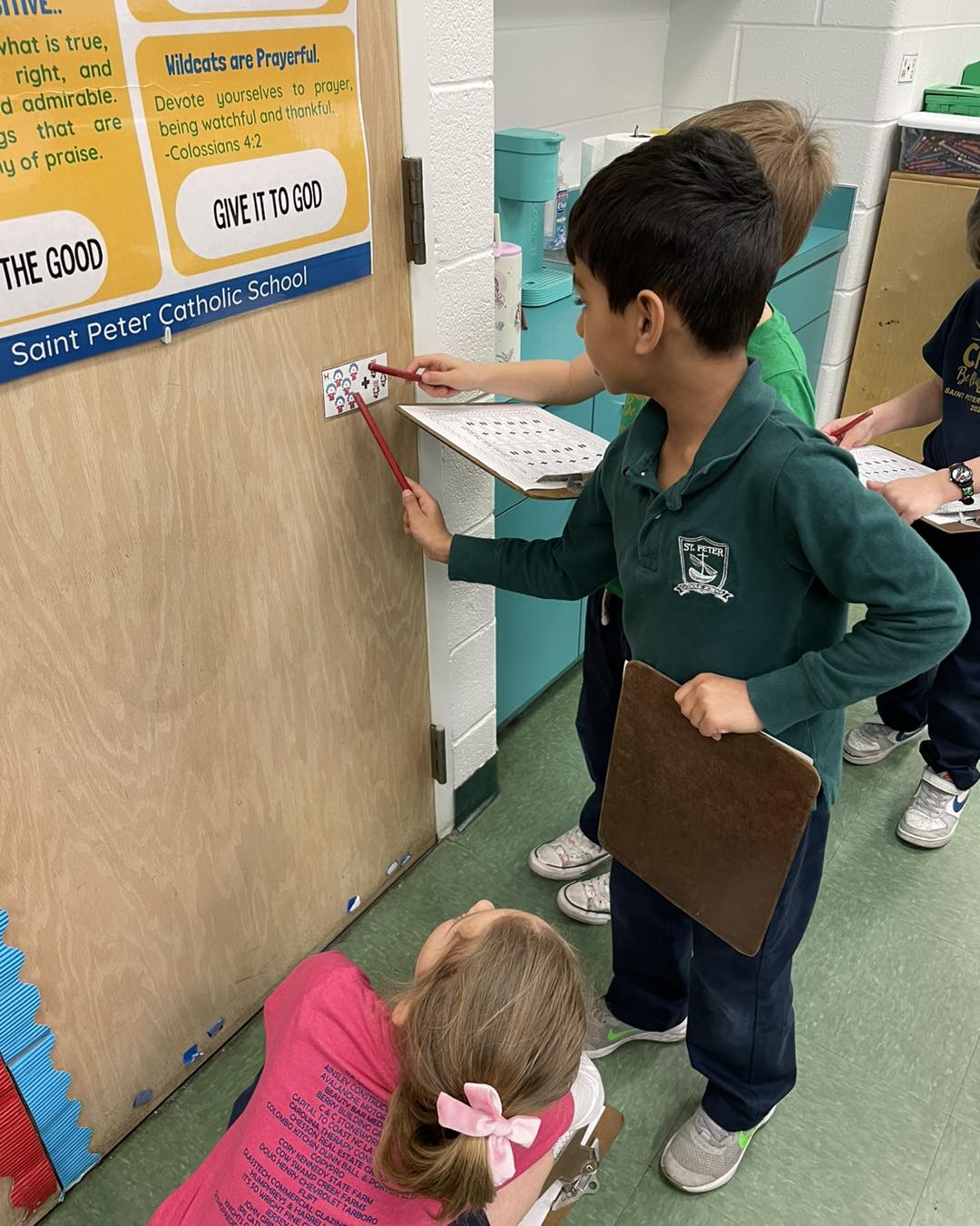 Students point to math clue while holding worksheets on clipboards
