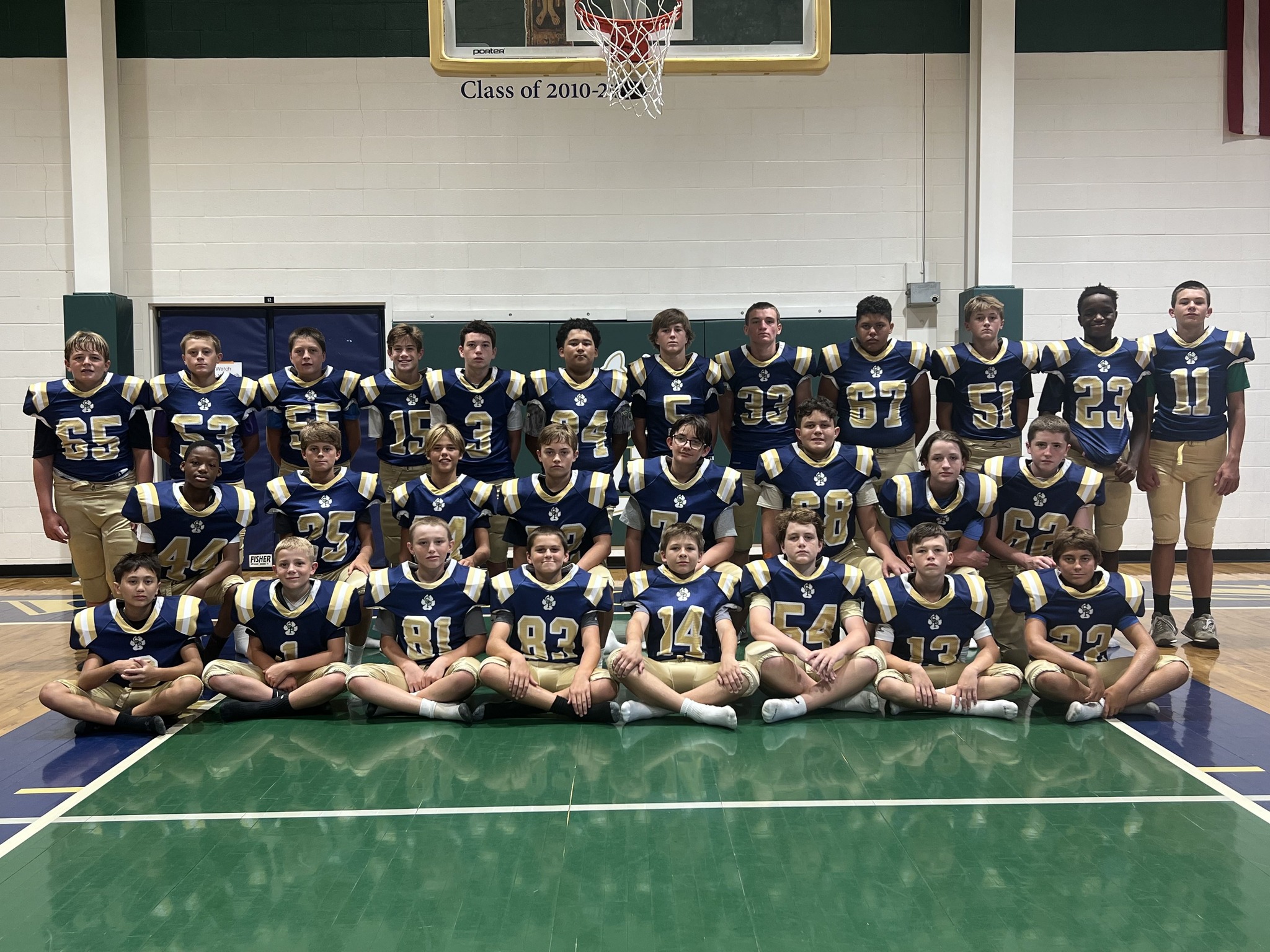 St Peter’s Catholic School football team, posing for a group shot in the gym, with front row sitting, second row kneeling, third row standing
