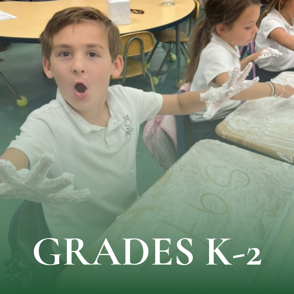 Kindergarten student showing his excitement of writing words on his desk using his fingers to spell the word “sat” in white whipped cream