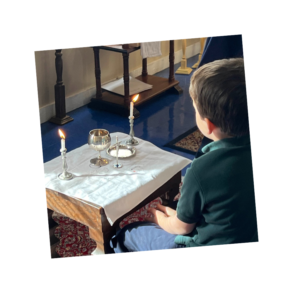 A boy sits in front of a play Mass set on a table