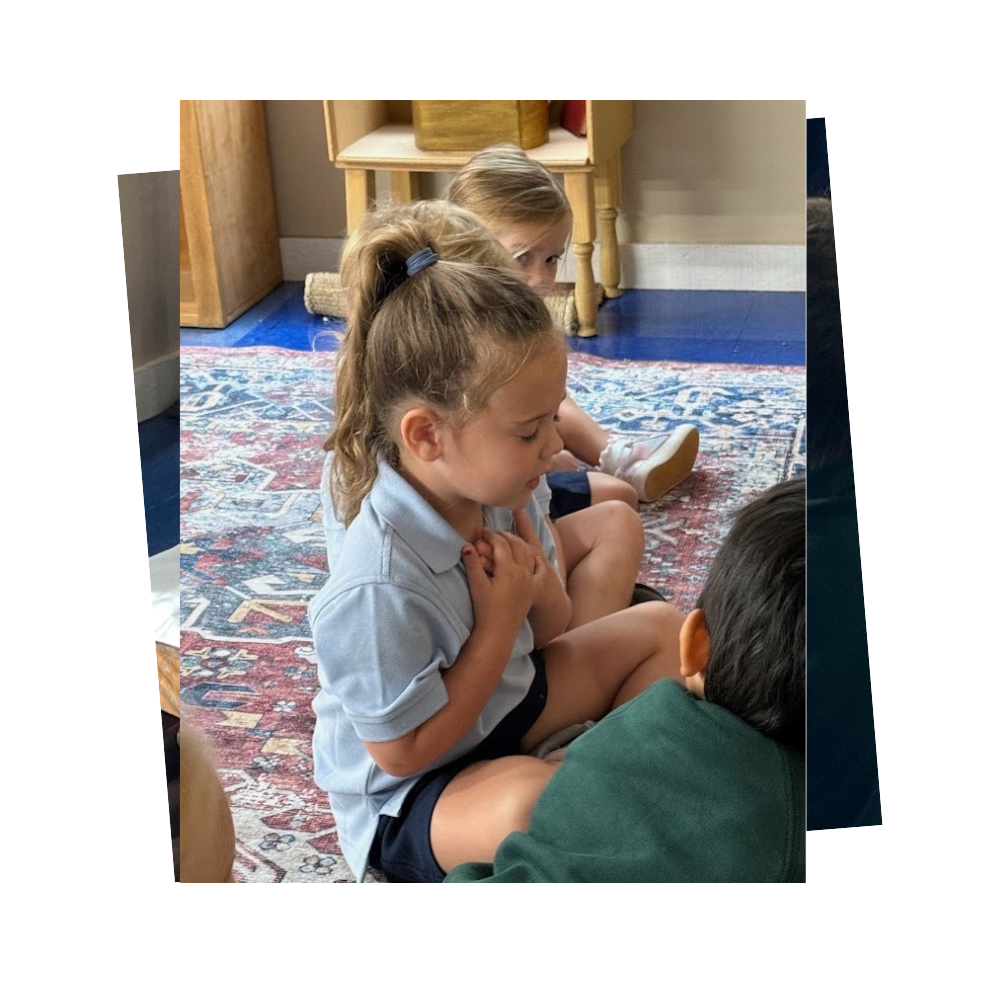 A young girl sitting on a carpet with her hands folded across her chest in prayer