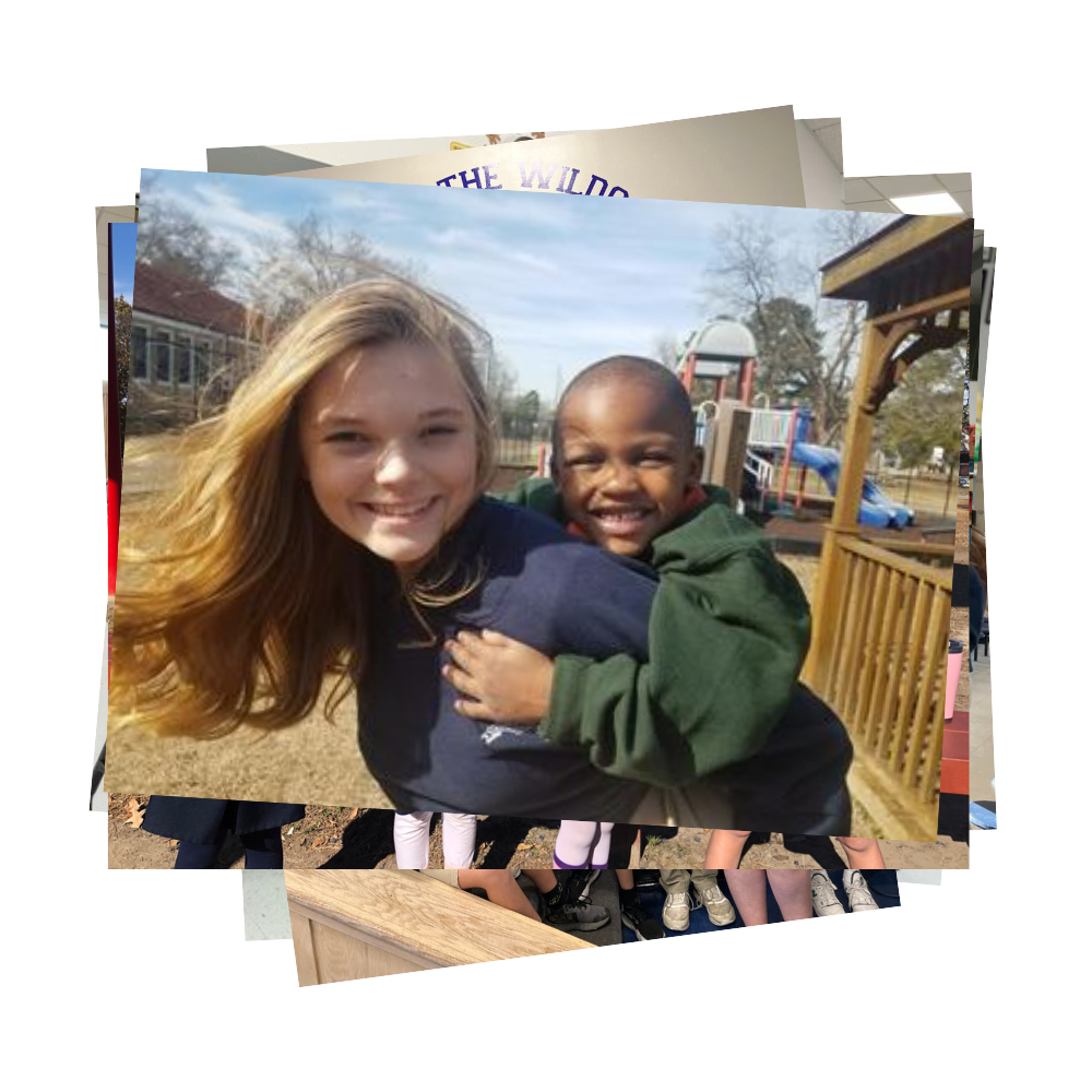 Student holding a younger student on her back by a playground
