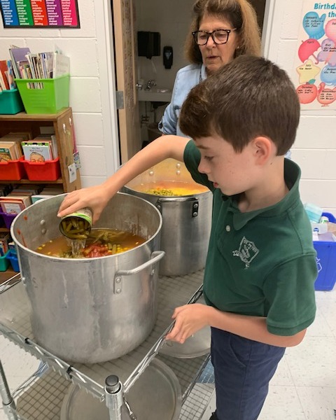Student emptying a can of soup into a pot