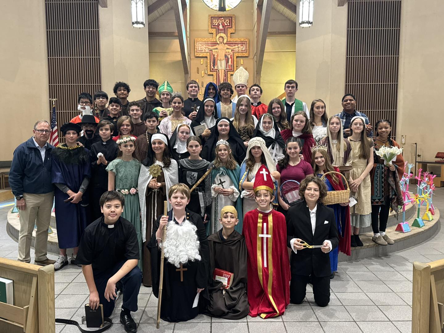Students dressed in All Saints Day costumes in front of the altar at church
