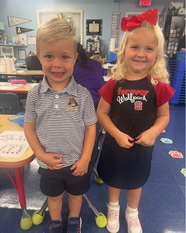 Preschool students wearing sports team shirts smiling at camera
