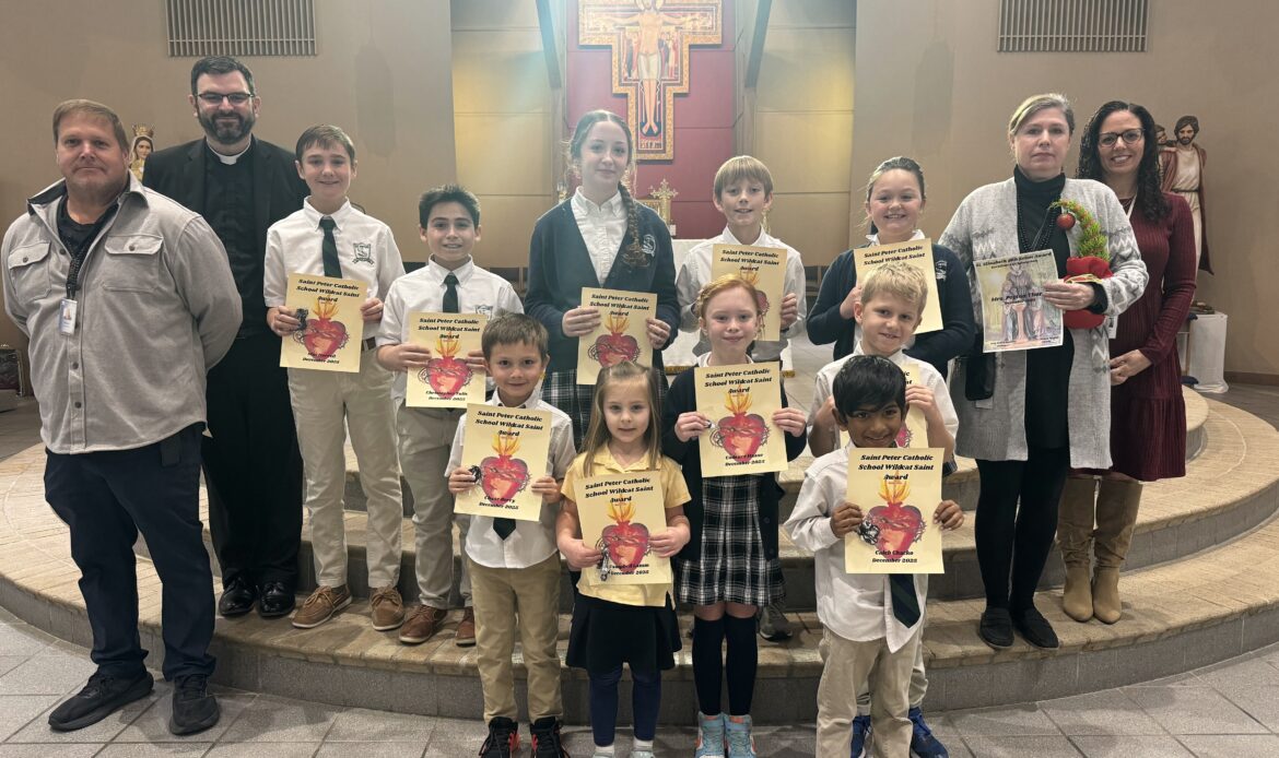 Students and faculty of St. Peter Catholic School smiling at the camera as they hold their Wildcat Saint awards.