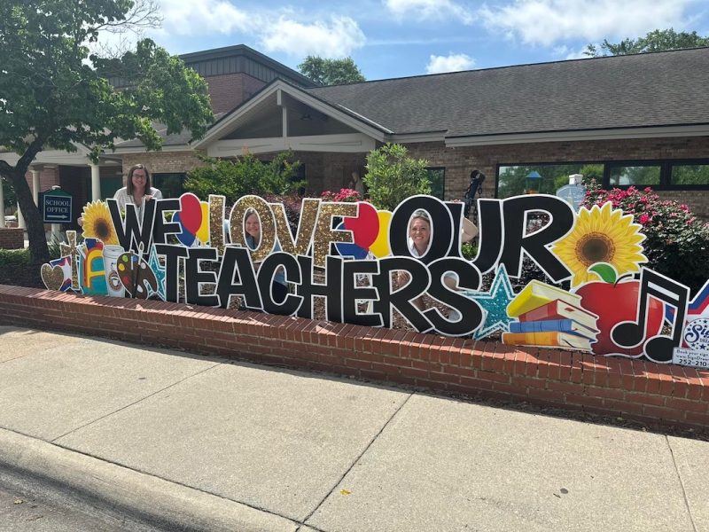 Teachers posing near sign that reads We love our teachers